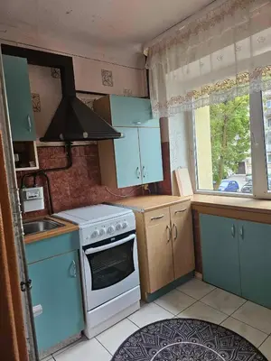 a kitchen with blue cabinets and a stove and a window at Suncity 2 apartamentai in Šiauliai