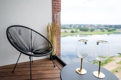 two wine glasses sitting on a table next to a chair at AMJ Royal Apartments - 120 - Royal Classic in Kaunas