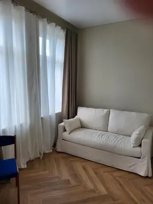 a living room with a white couch in front of a window at Greenhill Trio in Kaunas