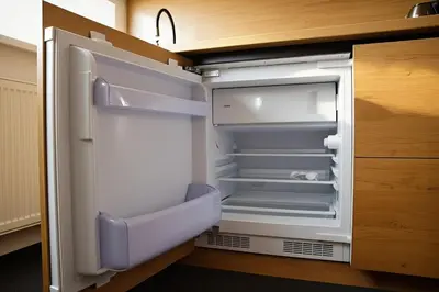 an empty refrigerator with its door open in a kitchen at Cozy Family Apartments in Druskininkai