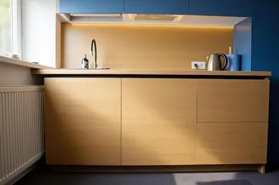 a kitchen with a wooden cabinet with a sink at Cozy Family Apartments in Druskininkai
