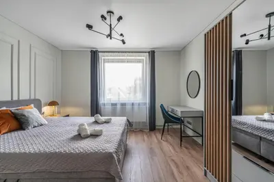 a bedroom with a bed and a desk and a mirror at Central Park Apartments in Birštonas