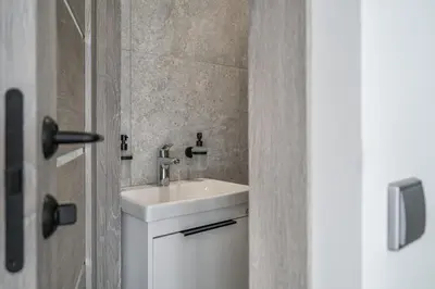 a bathroom with a white sink and a door at Central Park Apartments in Birštonas