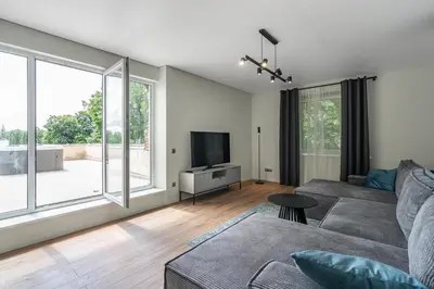 a living room with a couch and a tv at Central Park Apartments in Birštonas