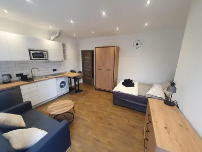 a living room with a blue couch and a kitchen at Urban Oasis Studios in Kaunas