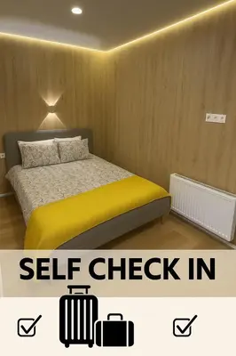 a bedroom with a bed with yellow sheets and two suitcases at 15 New Airport Apartment in Vilnius