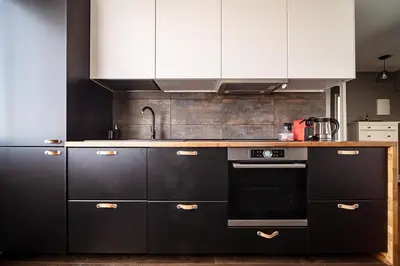 a kitchen with black appliances and white cabinets at Urban Oasis Apartments in Šiauliai