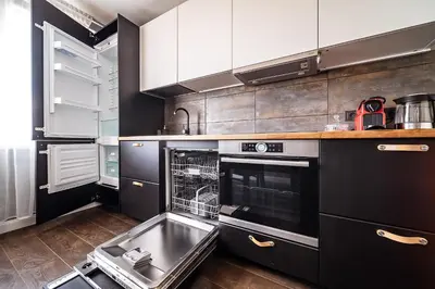 a kitchen with black and white cabinets and a dishwasher at Urban Oasis Apartments in Šiauliai