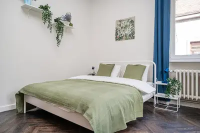 a white bedroom with a bed with a green blanket at Central Avenue Residence Kaunas in Kaunas