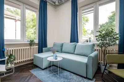 a blue couch in a living room with windows at Central Avenue Residence Kaunas in Kaunas