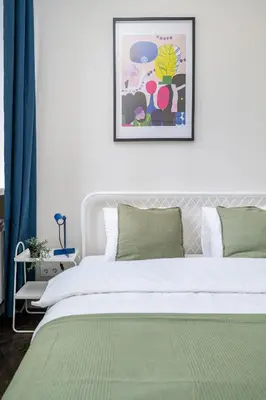 a bedroom with a white bed with a green blanket at Central Avenue Residence Kaunas in Kaunas