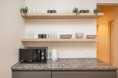 a kitchen with a microwave on a counter with dishes at Central Avenue Residence Kaunas in Kaunas