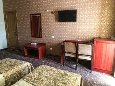 a hotel room with two beds and a desk and a television at Pas Radvila in Kaišiadorys