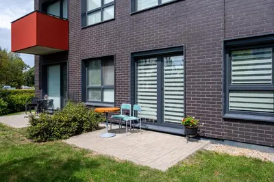 two chairs and a table in front of a building at Park's Edge apartment in Kaunas
