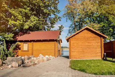 a wooden building next to a house with a driveway at Kambarių nuoma Žasliuose in Žasliai