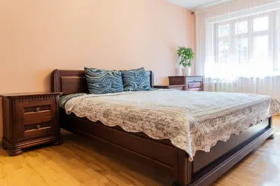 a bedroom with a bed and a nightstand and a window at Monic Apartments in Šiauliai