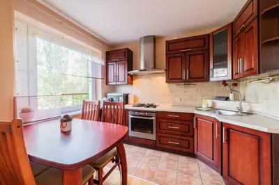 a kitchen with wooden cabinets and a table with a dining room at Monic Apartments in Šiauliai