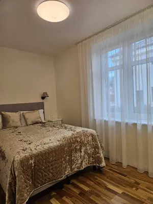 a bedroom with a bed and a large window at Suncity apartamentai in Šiauliai