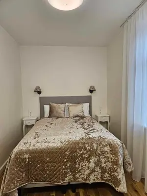 a bedroom with a large bed with two tables at Suncity apartamentai in Šiauliai