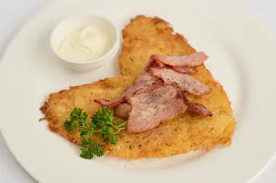 a white plate with a piece of fish with bacon at Dzūkijos dvaras in Alytus