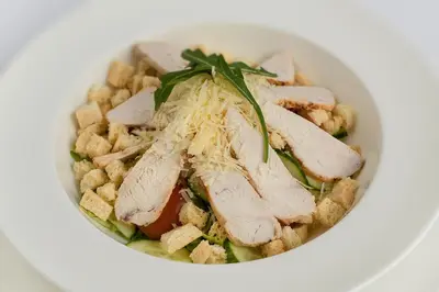 a white bowl of food with meat and vegetables at Dzūkijos dvaras in Alytus
