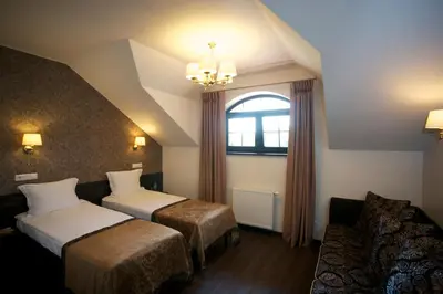 a hotel room with two beds and a couch at Dzūkijos dvaras in Alytus