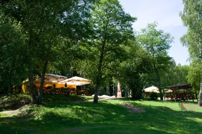 a park with tables and umbrellas in the grass at Dzūkijos dvaras in Alytus