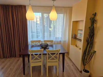 a dining room table with two yellow chairs and two lights at Čiurlionis Apartment Druskininkai in Druskininkai