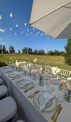 a long white table with plates and silverware at Provansalio dvaras in Babriškės