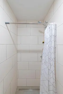 a shower in a bathroom with white tiles at Partizanų studio apartment #2 by Polo Apartments in Kaunas