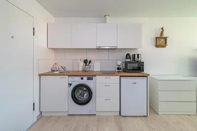 a kitchen with white cabinets and a washing machine at Partizanų studio apartment #2 by Polo Apartments in Kaunas
