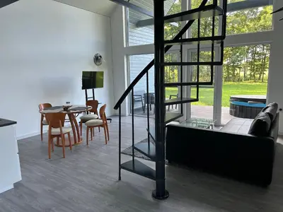 a living room with a spiral staircase and a table at Zanapolio ranča in Norvaišiai