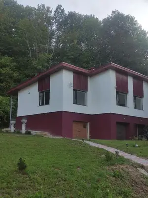 a red and white building with a grass yard at Rent Olamit in Karkazai