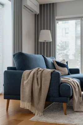 a blue couch with a blanket on it in a living room at D33 Vilnius - Brand New Luxury Apartment with Terrace, Garden, AC and Parking in Vilnius