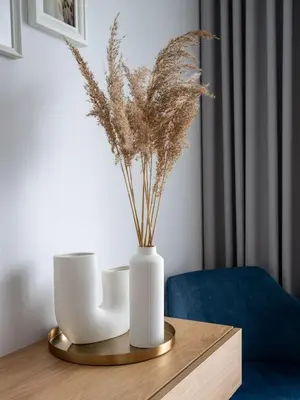a white vase on a wooden table with flowers in it at D33 Vilnius - Brand New Luxury Apartment with Terrace, Garden, AC and Parking in Vilnius