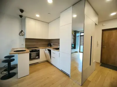 a kitchen with white cabinets and a black stool at Modern Urban Retreat & Private Parking in Vilnius