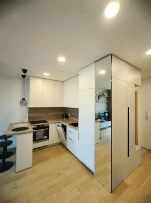 a large kitchen with white cabinets and a table at Modern Urban Retreat & Private Parking in Vilnius