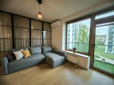 a living room with a couch and a large window at Modern Urban Retreat & Private Parking in Vilnius