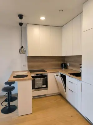 a kitchen with white cabinets and a counter with a stool at Modern Urban Retreat & Private Parking in Vilnius