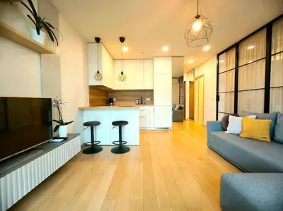 a living room with a couch and a kitchen at Modern Urban Retreat & Private Parking in Vilnius