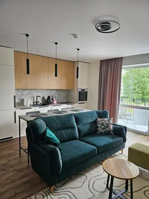 a living room with a green couch and a kitchen at Milda's apartment Kaunas in Kaunas