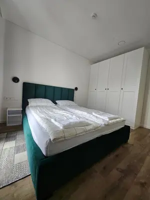 a bedroom with a bed with a green headboard and white cabinets at Milda's apartment Kaunas in Kaunas
