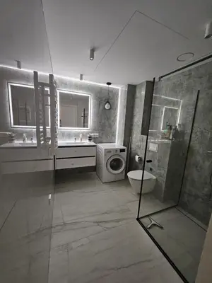 a bathroom with a shower and a sink and a washing machine at Milda's apartment Kaunas in Kaunas