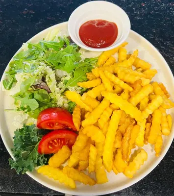 a plate of french fries and a salad withetchup at Vėjukai in Viduklė