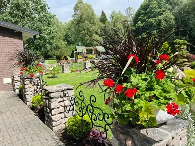 a garden with red flowers in a stone wall at Vėjukai in Viduklė