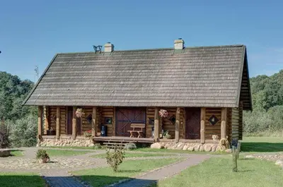 a large log cabin with a large roof at Šnekučių kaimas in Miežonys