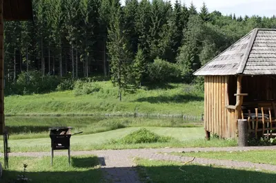 a bbq and a building with a sign in the grass at Šnekučių kaimas in Miežonys