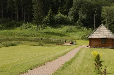 a cabin in the middle of a field with a dirt road at Šnekučių kaimas in Miežonys