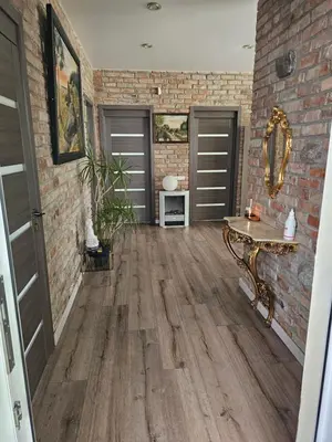 a hallway with a brick wall and a wooden floor at Apartamentai keliaujantiems į Kauna in Garliava