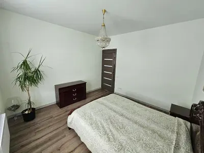 a bedroom with a bed and a dresser and a plant at Apartamentai keliaujantiems į Kauna in Garliava
